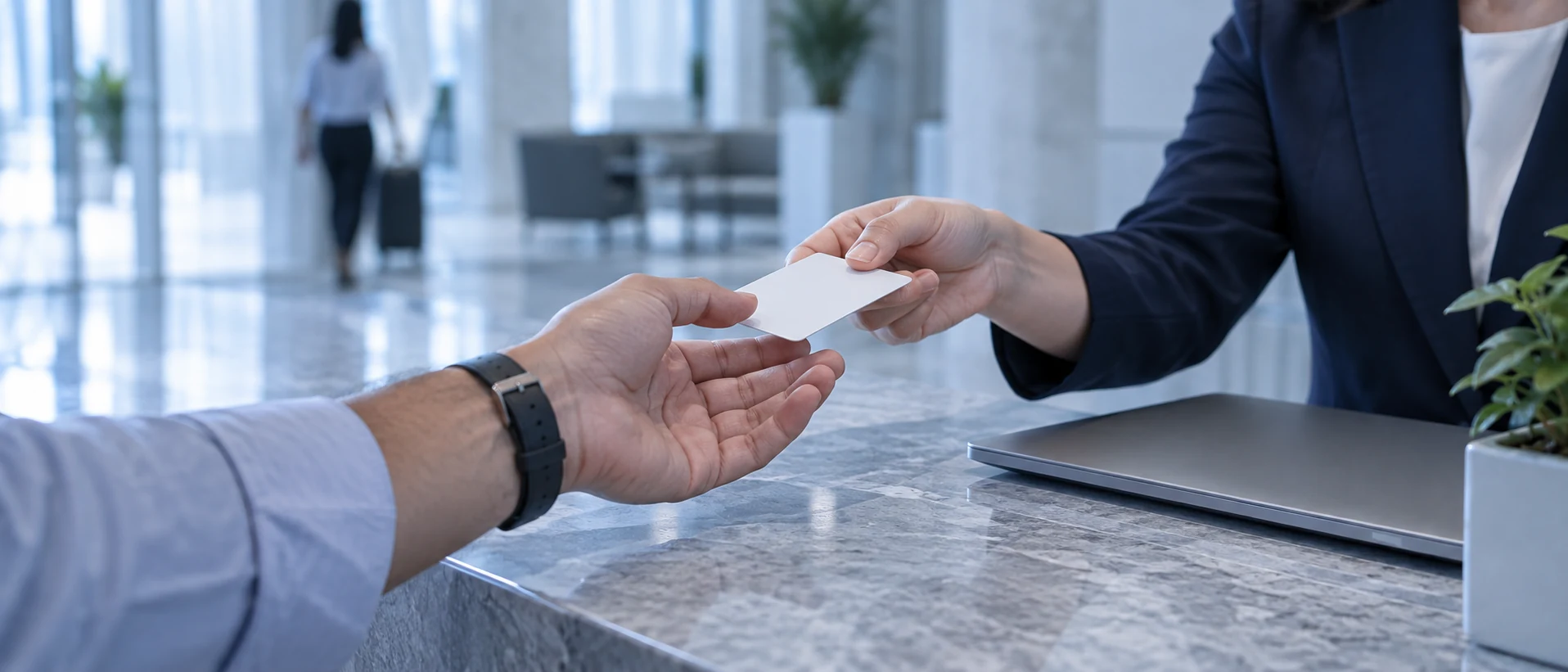 Cận cảnh hai bàn tay trên quầy lễ tân bằng đá: nhân viên trả lại một tấm thẻ trống cho khách.