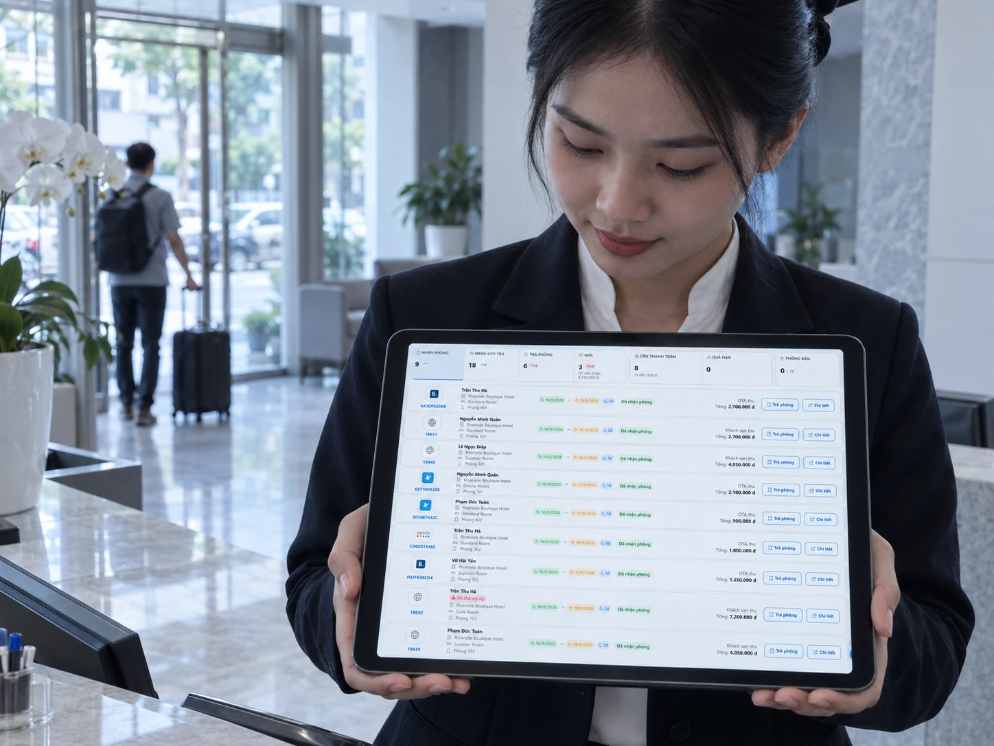 Nhân viên lễ tân đứng sau quầy, cầm máy tính bảng đang mở bảng điều khiển trong ngày của Roomrise.